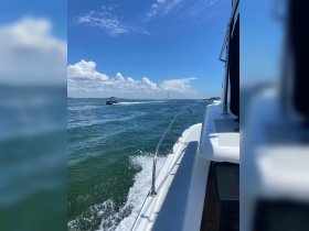 A scenic view from a boat cruising through vibrant blue waters, showcasing the beauty of the ocean and nearby vessels in motion.