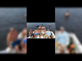 A lively group of friends enjoys a fun day on the water, relaxing on a pontoon boat while others swim nearby — perfect for summer adventures and celebrations.