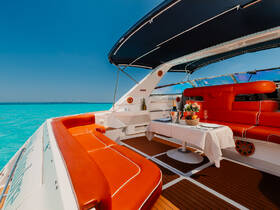 A beautifully designed interior of a boat featuring vibrant orange seating and a dining table set for a luxurious experience on the water, perfect for relaxing and entertaining.