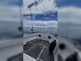 A clean and spacious view of the helm area on a fishing boat, showcasing the deck and equipment, perfect for a day out on the water.
