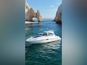A stunning aerial view of a sleek yacht navigating through crystal-clear waters near iconic rock formations, perfect for luxury boating experiences.