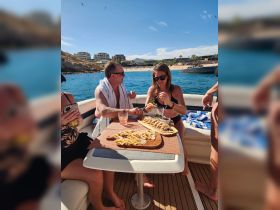 A lively group enjoys delicious food and cocktails aboard a boat, capturing the essence of a perfect day on the water with friends.