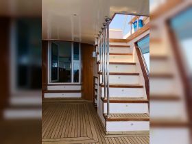 Interior view of a boat's staircase leading to the helm area, showcasing elegant wooden finishes and spacious design — perfect for comfortable cruising.