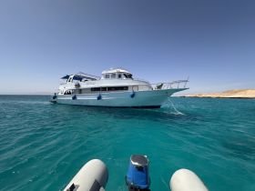 A stunning view of a yacht anchored in crystal-clear waters, showcasing its sleek design against a picturesque backdrop.