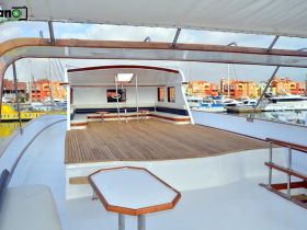 A spacious interior view of a yacht's deck area, showcasing comfortable seating and a polished wooden floor, perfect for relaxing while enjoying the marina scenery.