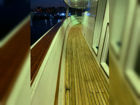 A serene view of the polished wooden deck of a boat at night, showcasing the elegant interior design and ambiance perfect for evening cruises.