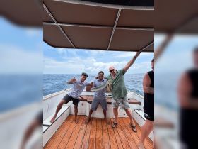 A lively group celebrates their fishing catch aboard a boat, showcasing the joy of a successful day on the water.