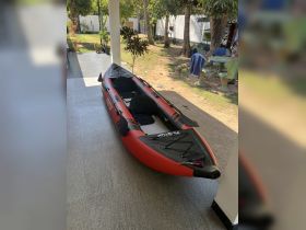 An inflatable kayak is displayed in a shaded outdoor area, ready for adventure on the water. Perfect for exploring lakes and rivers.