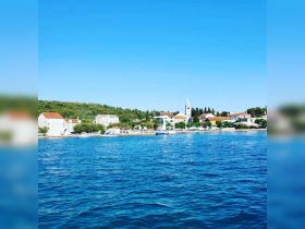 A picturesque view of a charming coastal town with clear blue waters and lush greenery, perfect for exploring by boat.