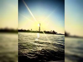 A stunning sunset view featuring a lighthouse silhouetted against the vibrant sky, capturing the serene beauty of coastal scenery.