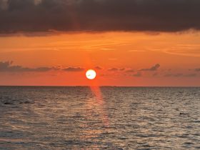 A breathtaking sunset over the ocean, casting vibrant colors across the sky and water — a perfect backdrop for evening boat cruises.