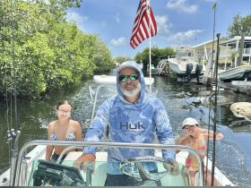 A family enjoys a day of boating in a scenic canal, with smiles and fishing gear ready for adventure.
