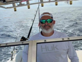 A man stands at the helm of a fishing boat, ready for an adventure on the open ocean — perfect for sport fishing enthusiasts.