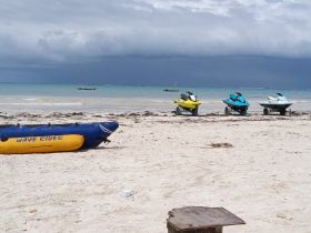 A vibrant display of jet skis and an inflatable banana boat on the beach, perfect for water sports enthusiasts looking to enjoy a day of fun in the sun.