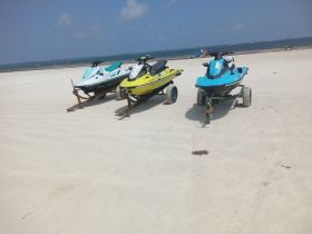 Three colorful jet skis are parked on the beach, ready for an exciting day of water sports and adventure.