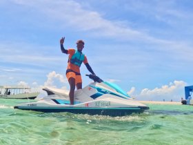 A joyful individual rides a jet ski in clear waters, showcasing the thrill of water sports and adventure on the beach.