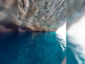 A view of a rocky overhang above clear blue waters, showcasing the natural beauty of the underwater environment.