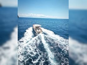 A stunning aerial view of a speedboat cruising through clear blue waters, showcasing the vessel's sleek design and the beauty of the open sea.
