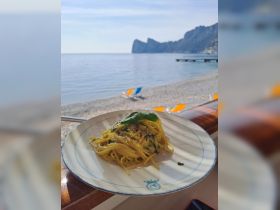 A delicious plate of pasta served with a stunning beach view, perfect for enjoying a meal while soaking in the coastal atmosphere.