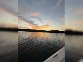 A serene sunset view over calm waters, showcasing the beauty of nature from the deck of a boat.