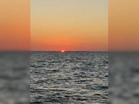 A stunning sunset over calm waters, creating a picturesque backdrop perfect for evening boat cruises or romantic getaways.