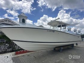 A sleek speedboat displayed on a dock, showcasing its elegant design against a backdrop of fluffy clouds and a charming building.