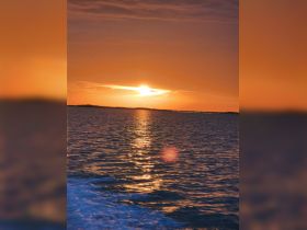 A serene sunset over calm waters, creating a picturesque scene perfect for relaxation and reflection.
