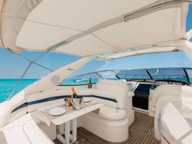 A beautifully designed interior of a yacht featuring a cozy seating area and helm, perfect for relaxing and enjoying the stunning views of the turquoise waters.