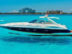 A sleek speedboat glides through crystal-clear turquoise waters, showcasing its elegant design against a stunning coastal backdrop.