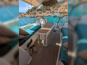 A cozy interior view of a boat's helm and seating area, featuring comfortable cushions and a stylish wooden table, perfect for relaxing while cruising.