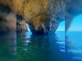 A stunning view of a cave along the coastline, with boats visible in the distance, showcasing the beauty of the water and natural formations — perfect for eco tours and scenic adventures.
