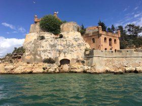 A stunning view of a historic fortress perched on a rocky coastline, surrounded by clear turquoise waters — a perfect destination for sightseeing and exploration.