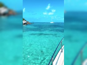 A stunning view of turquoise waters with a sailboat in the distance, perfect for showcasing the beauty of island destinations.