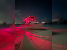 A striking speedboat illuminated with red lights, docked on a sandy beach at night, showcasing a unique nighttime boating experience.