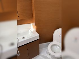 A clean and modern boat bathroom featuring a toilet and sink, showcasing the practical amenities available onboard.
