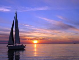 A serene sunset view of a sailboat gliding across calm waters, creating a picturesque scene perfect for evening cruises.