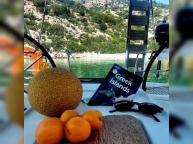 A selection of fresh fruits and a travel guidebook on a boat, perfect for enjoying a relaxing day on the water in the Greek Islands.