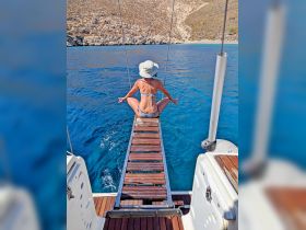 A woman enjoys a moment of relaxation on a boat, sitting on the swim platform with stunning blue waters in the background — perfect for tranquil boating experiences.