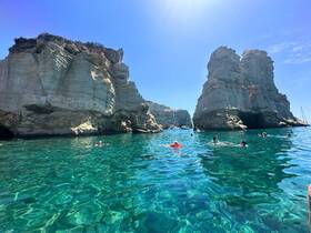 A lively group enjoys swimming in crystal-clear waters surrounded by stunning rock formations — a perfect day for exploration and relaxation in a picturesque setting.
