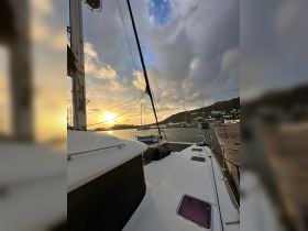 A serene view of a catamaran docked at sunset, showcasing the vessel's sleek design against a picturesque harbor backdrop.