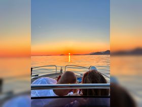 A couple enjoys a romantic sunset view from their boat, creating a perfect backdrop for memorable moments on the water.