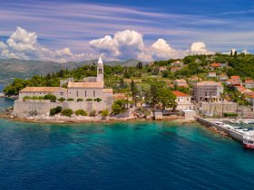 A stunning aerial view of a picturesque coastal village with historic architecture and lush greenery, perfect for exploring the beauty of the Adriatic coastline.