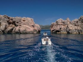 A scenic view of boats navigating through rocky coastal formations, showcasing the beauty of the marine landscape and adventure on the water.