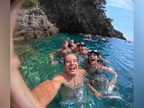 A lively group of friends enjoys a fun day swimming and snorkeling in crystal-clear waters, capturing joyful moments in a beautiful natural setting.