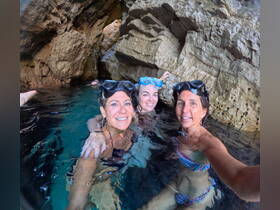 Three friends enjoy snorkeling in a stunning cave, capturing a memorable moment in the crystal-clear waters. Perfect for adventure seekers and group outings.
