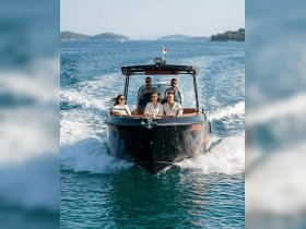 A lively group enjoys a thrilling boat ride, showcasing the joy of cruising on clear waters with stunning scenery in the background.