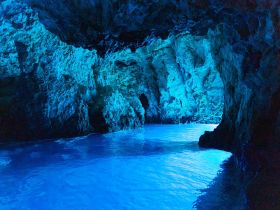 A stunning view of a cave with vibrant blue waters reflecting off the rocky walls, showcasing the natural beauty of this unique landmark.