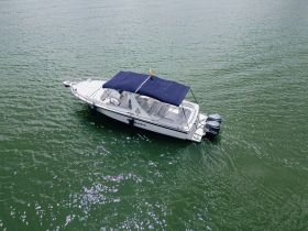 Aerial view of a sleek speedboat anchored in calm waters, showcasing its elegant design and spacious canopy — perfect for leisurely outings on the water.