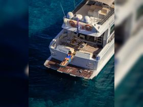 A woman relaxes on the back of a luxurious yacht, soaking up the sun against a stunning backdrop of turquoise waters — an ideal scene for summer getaways or private charters.