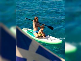 A mother and her son enjoy paddleboarding together in crystal-clear waters, creating unforgettable summer memories on the water.